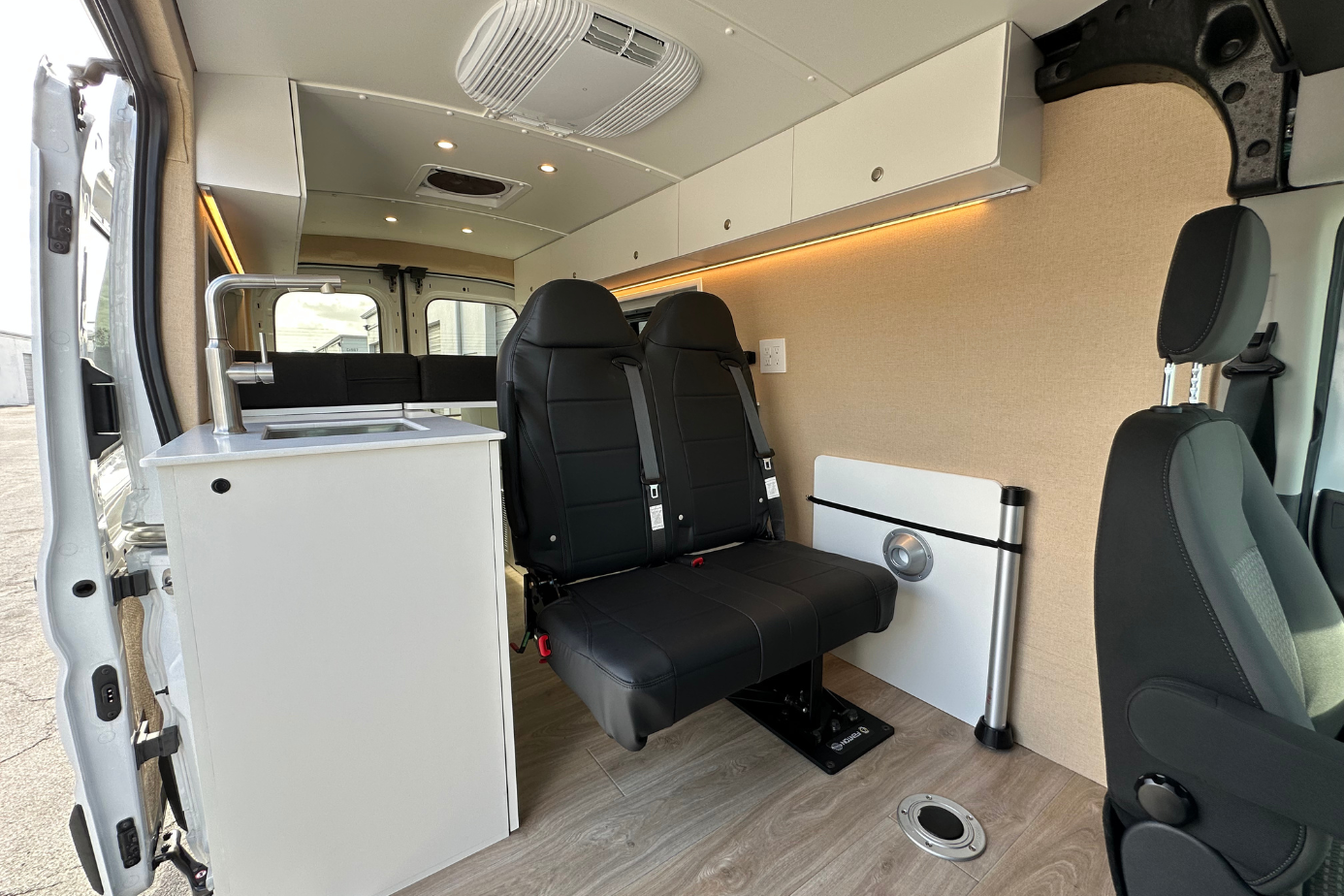 Custom camper van conversion interior in Florida with bench seating, kitchenette, cabinets and LED lighting